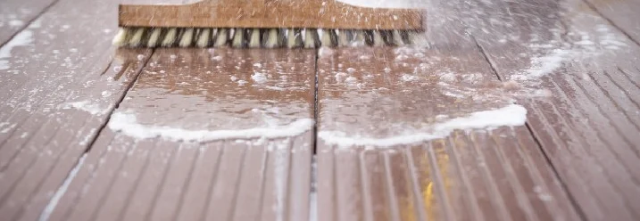 Holzterrasse wird mit Bürste gereinigt